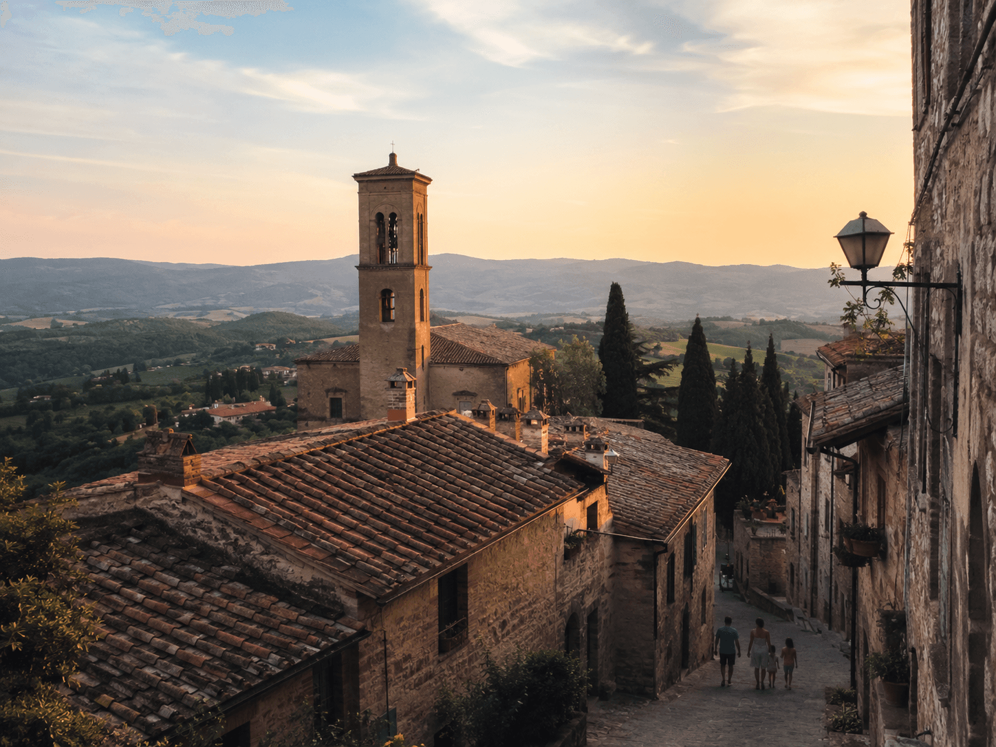 Vista de uma cidade da Toscana ao entardecer, com telhados de terracota e colinas ao fundo